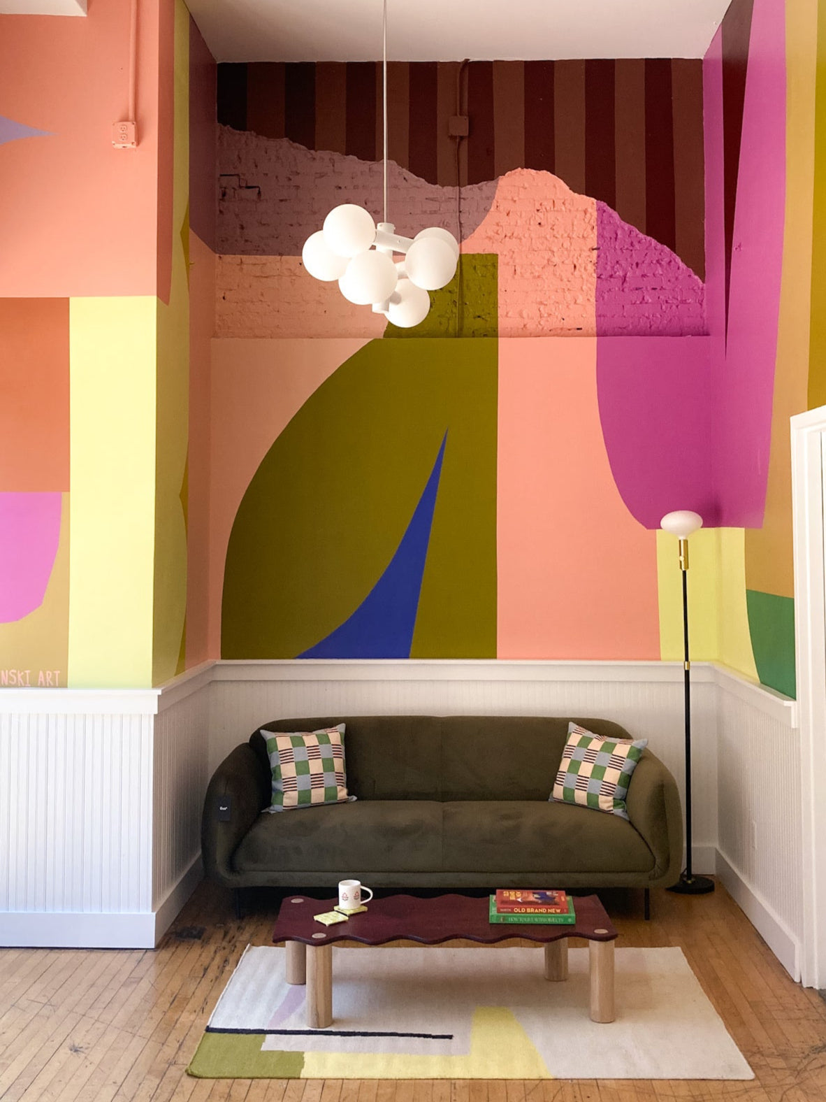 Modern living room with colorful abstract wall art and a green sofa.