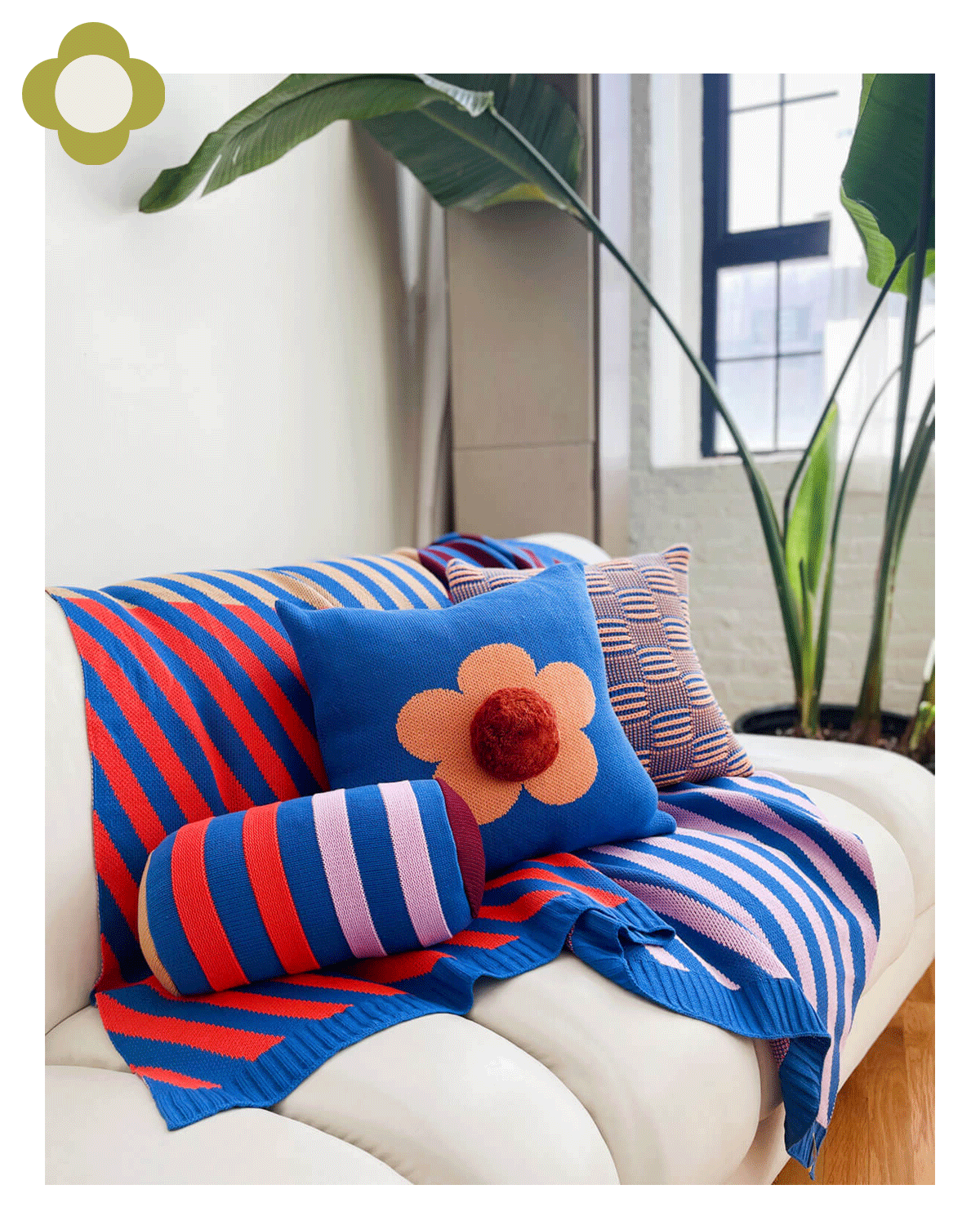 sofa with red and blue stripe blanket and flower pillow