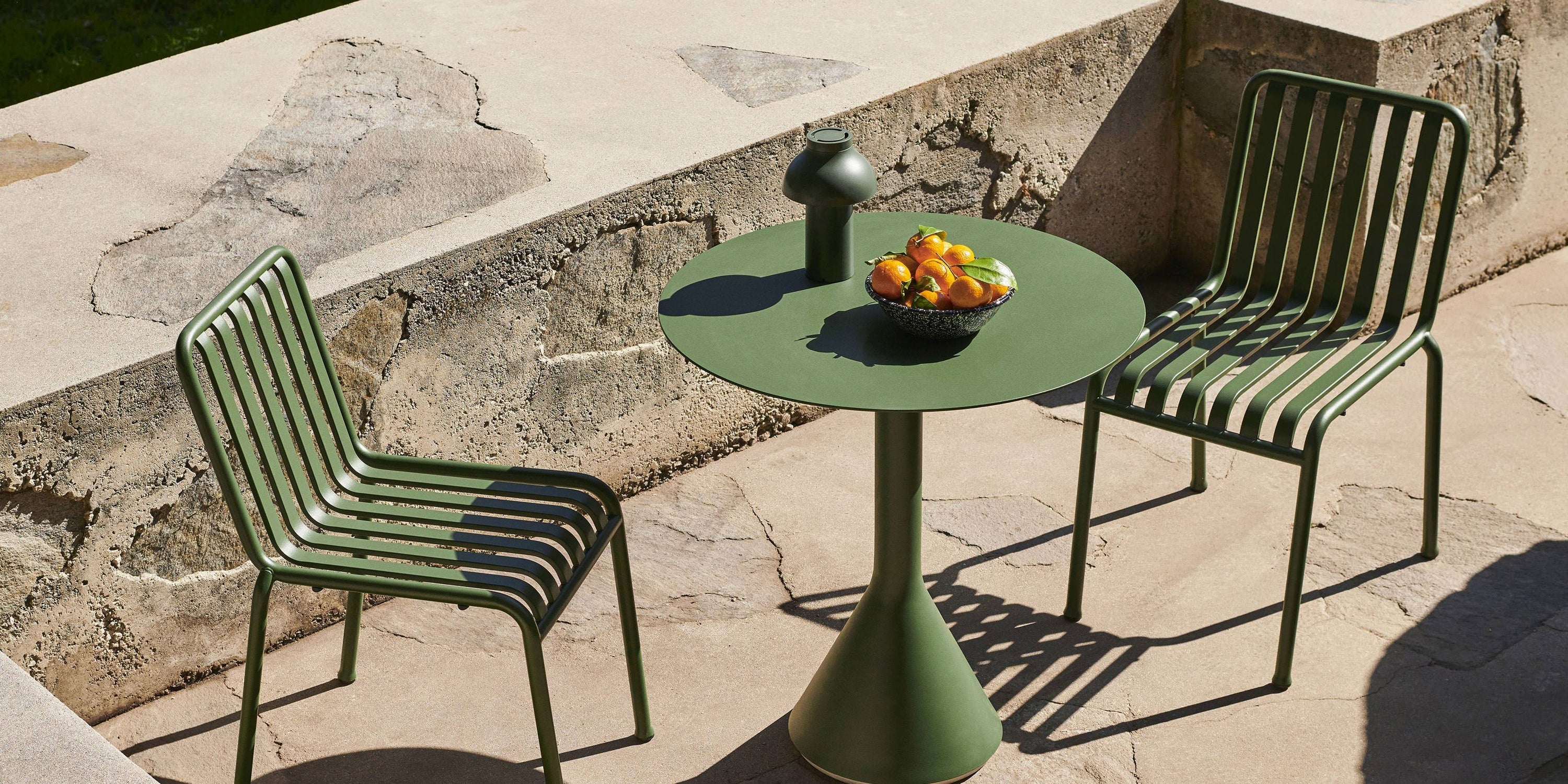Outdoor green metal chairs with bowl of oranges on table